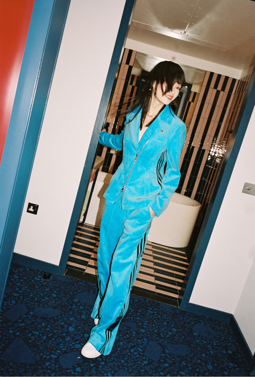 Model walking out of the bathroom with a Blue Version velvet suit and Stan Smiths.