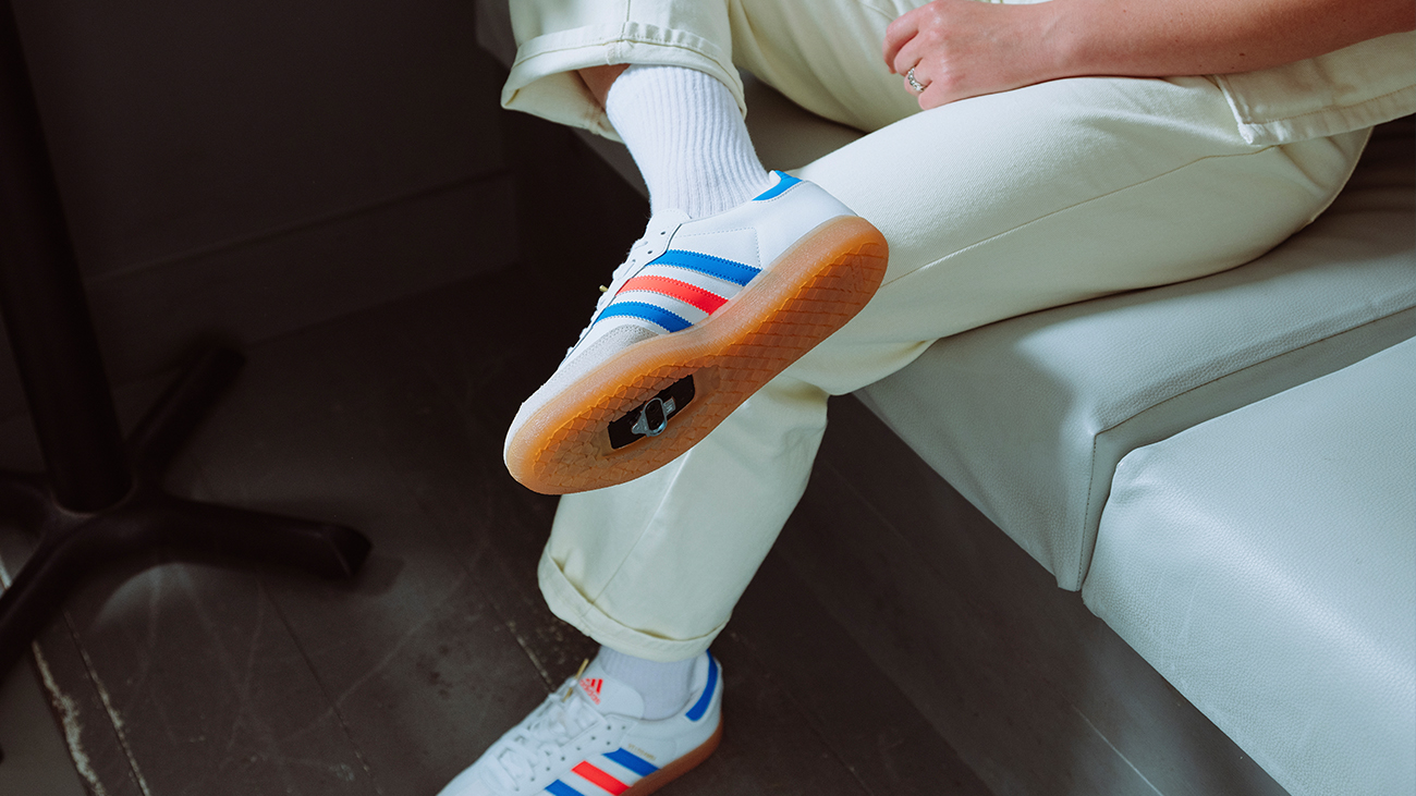 A women sits casually in a café with her legs crossed showing the underisde of her cycling shoes.