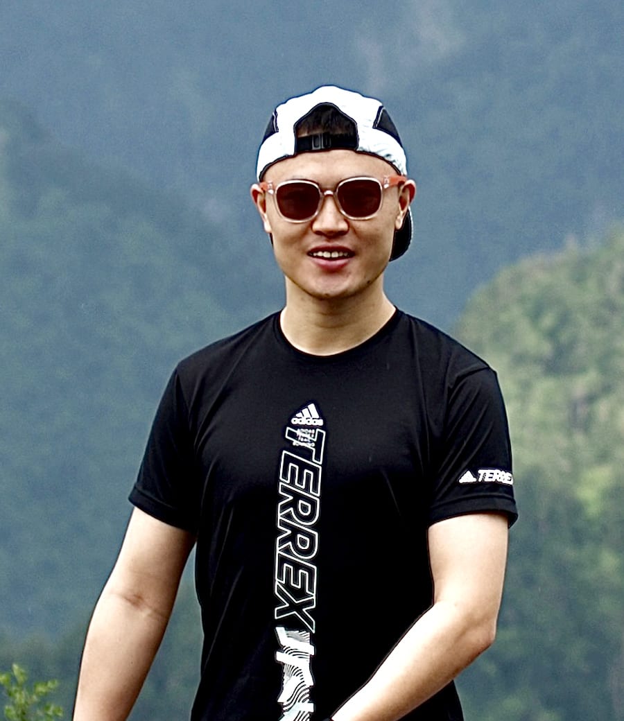 Ein chinesischer Trailrunner, der seine Kappe verkehrt herum aufhat und eine Sonnenbrille trägt