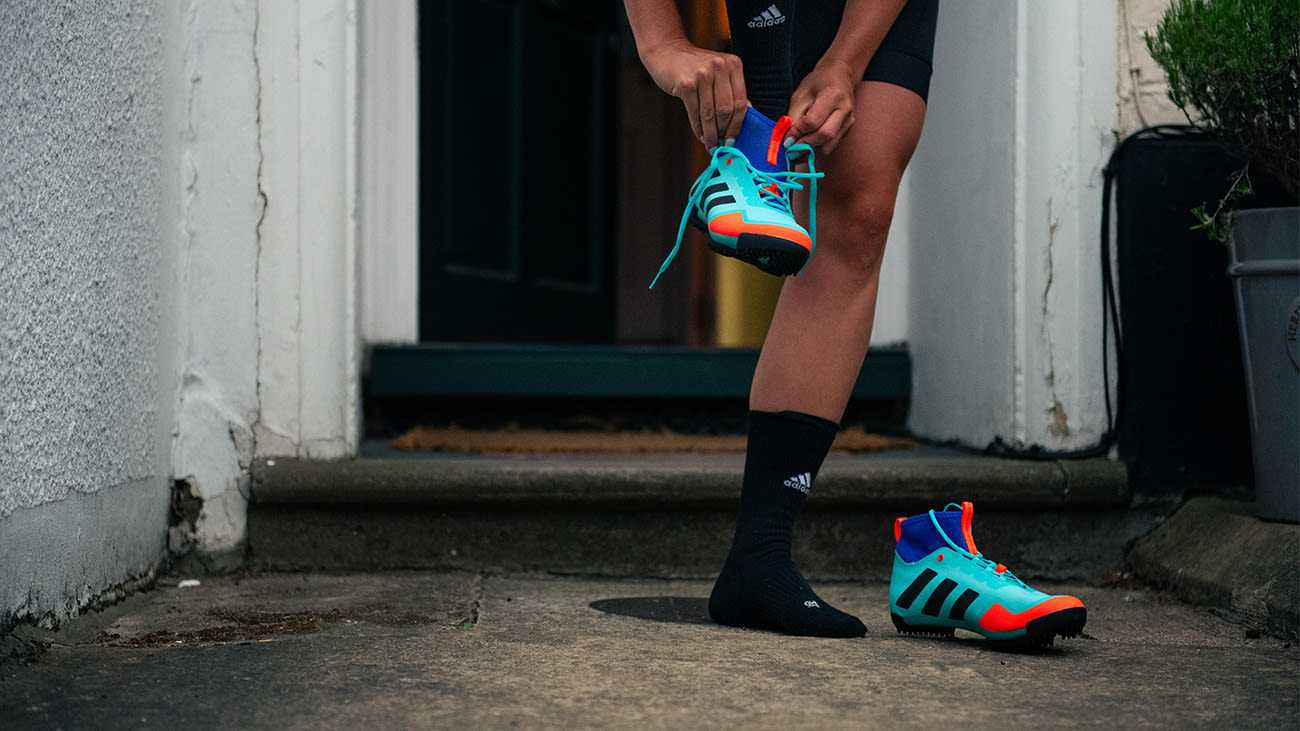fw21-cycling-mental-health-blog-body-1 A woman stood on a front porch putting on cycling shoes
