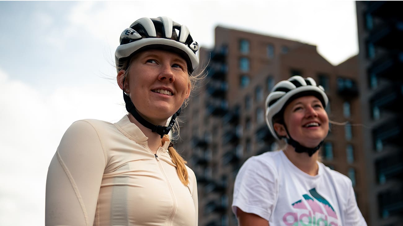 Two women in bike helmets in a city setting