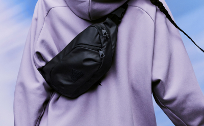 A black adidas bag worn over a light purple adidas Z.N.E. hoodie.