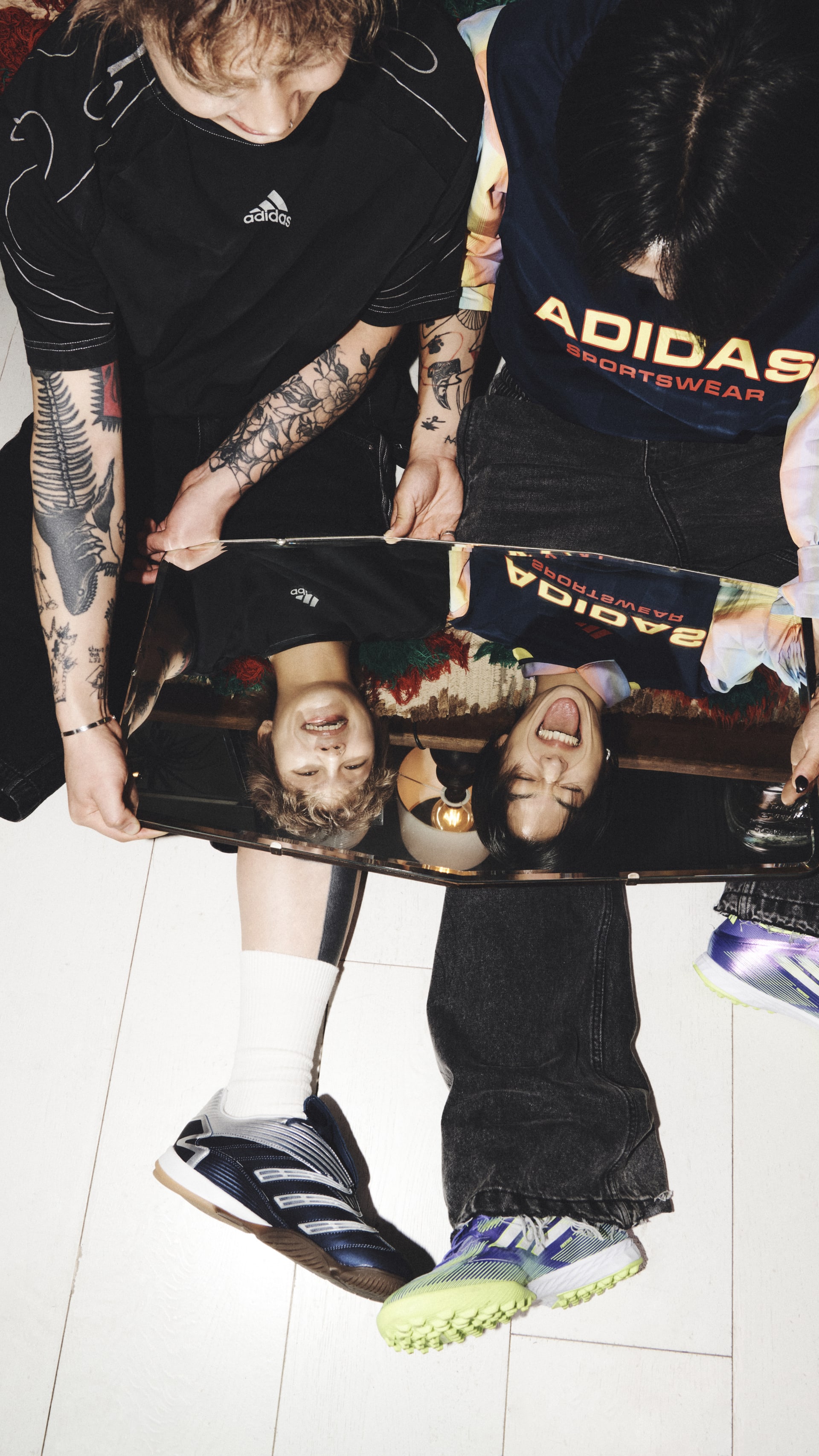 The image shows a person wearing Adidas sportswear, with tattoos visible on their arms, standing in front of various sports equipment and accessories.