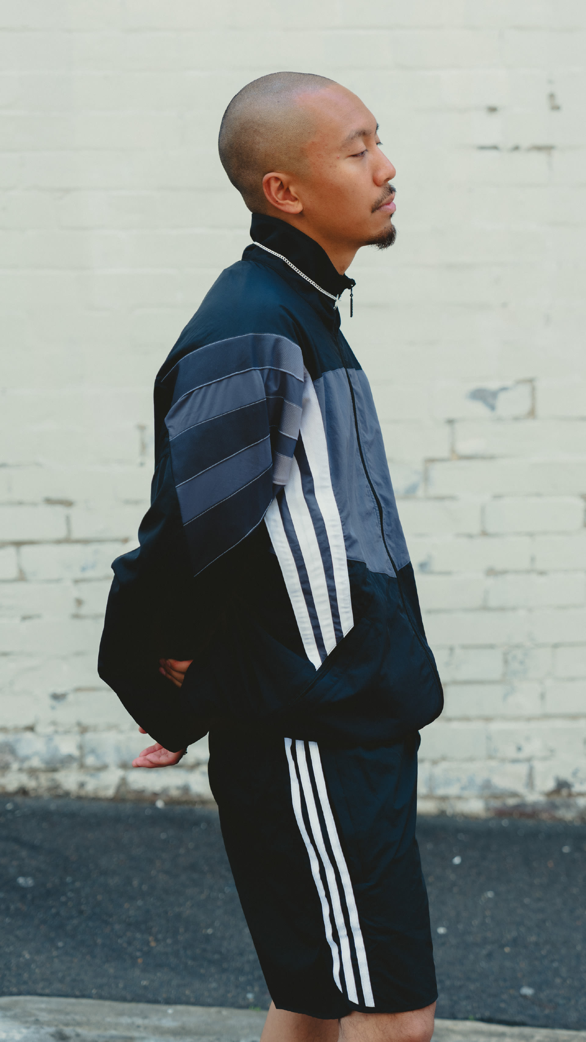 The image shows a person wearing a navy blue and white striped jacket, standing in front of a blurred background that appears to be a city street or urban setting.