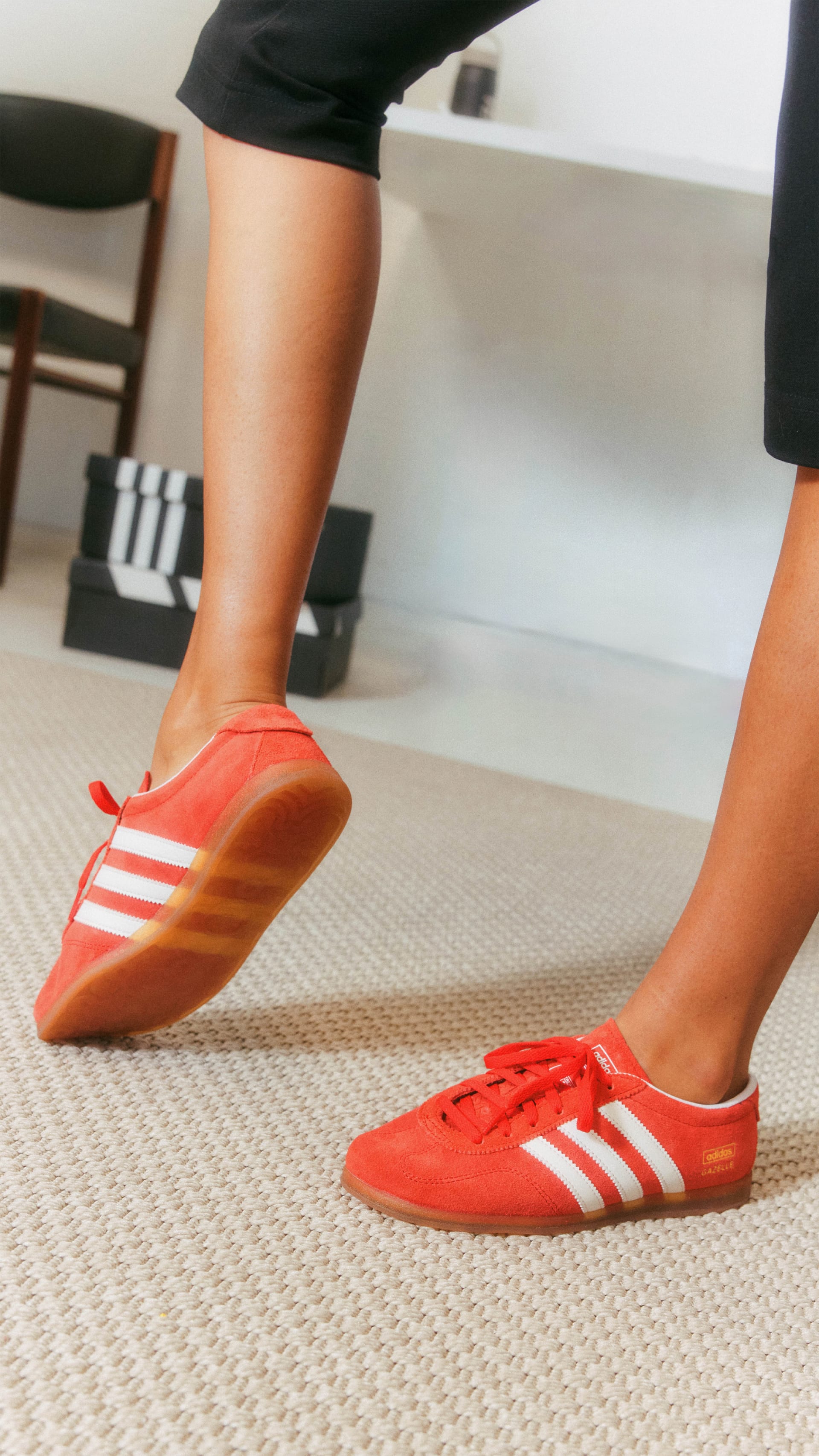 The image shows a person's lower body wearing bright red and white athletic shoes, standing on a carpeted floor in what appears to be an indoor setting.