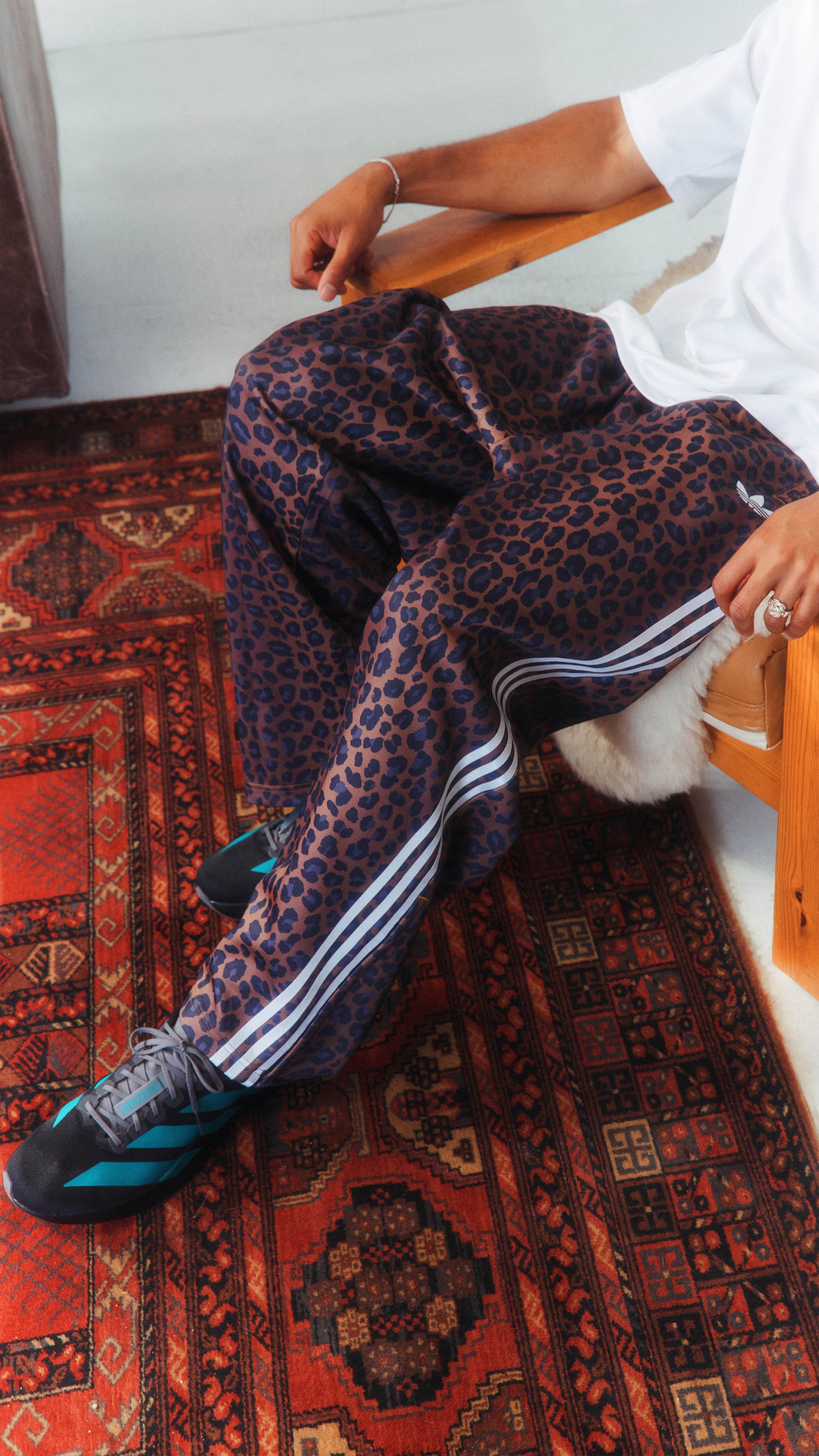 The image shows a person's legs and feet wearing leopard print leggings and colorful patterned socks, resting on a vibrant, ornate rug.
