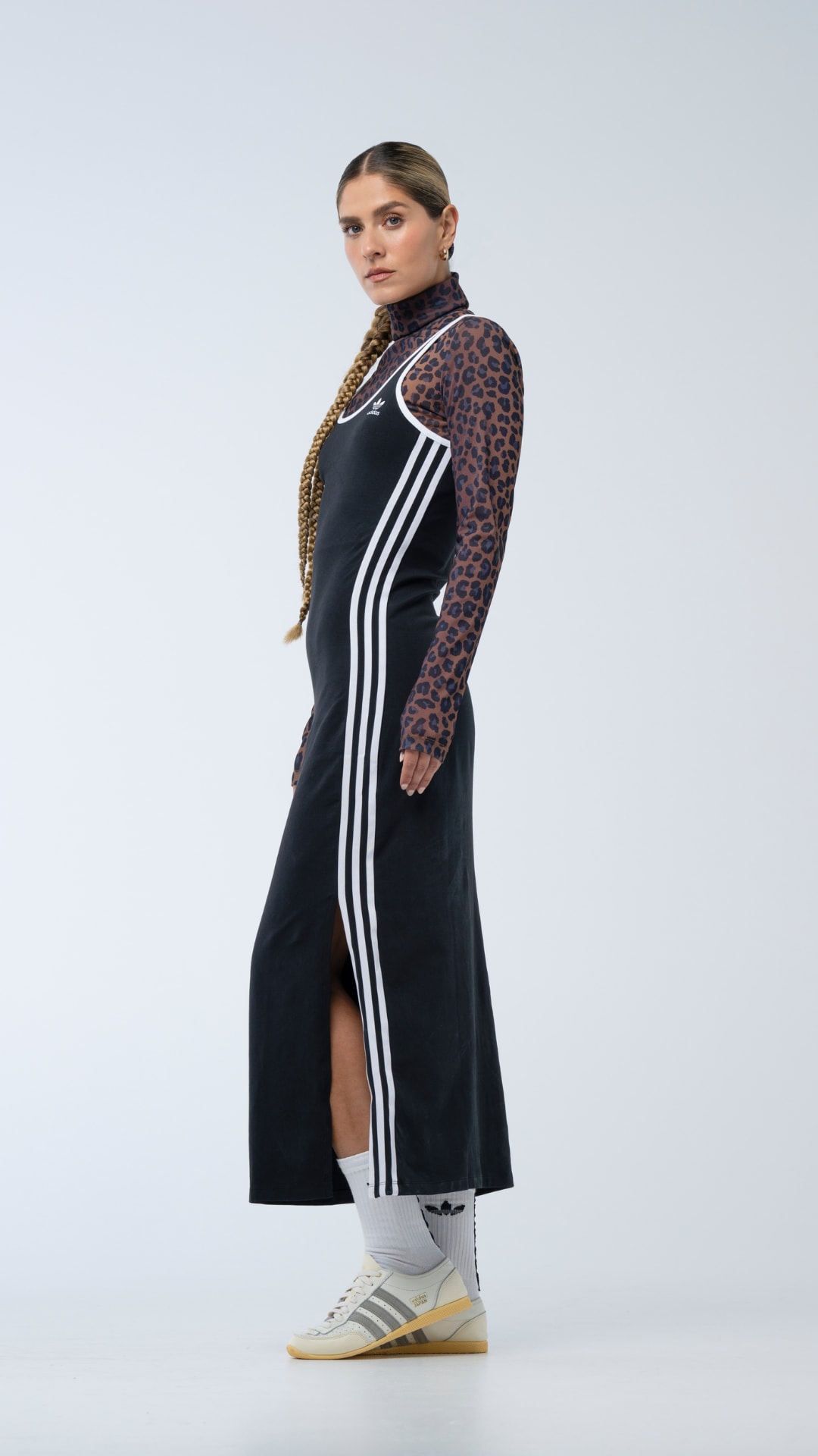 A person wearing a black dress with white stripes, standing against a plain background.