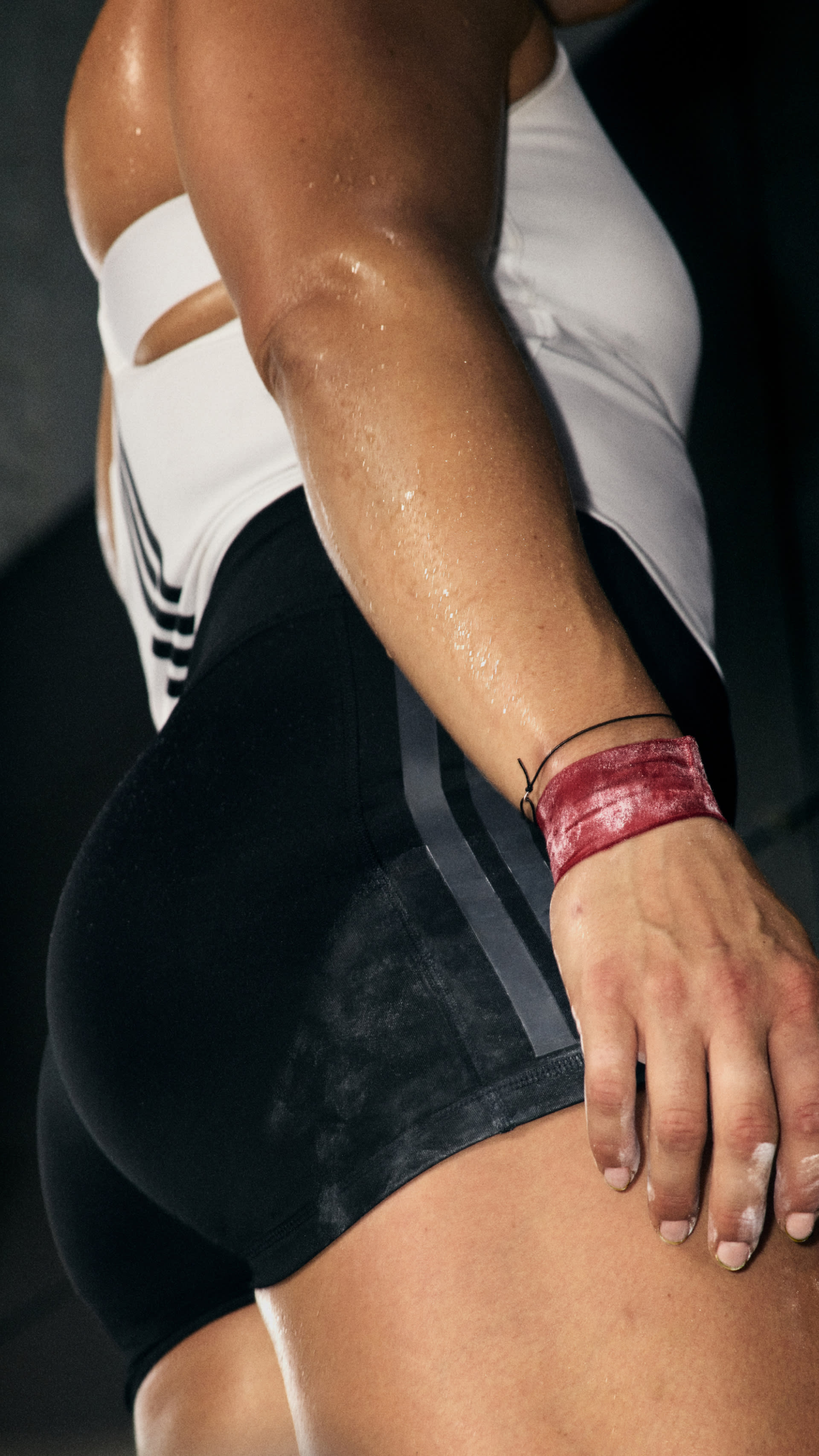 The image shows a person's arm and torso, with a white athletic top and a pink wristband visible. The background appears to be dark, creating a focused and dramatic composition.