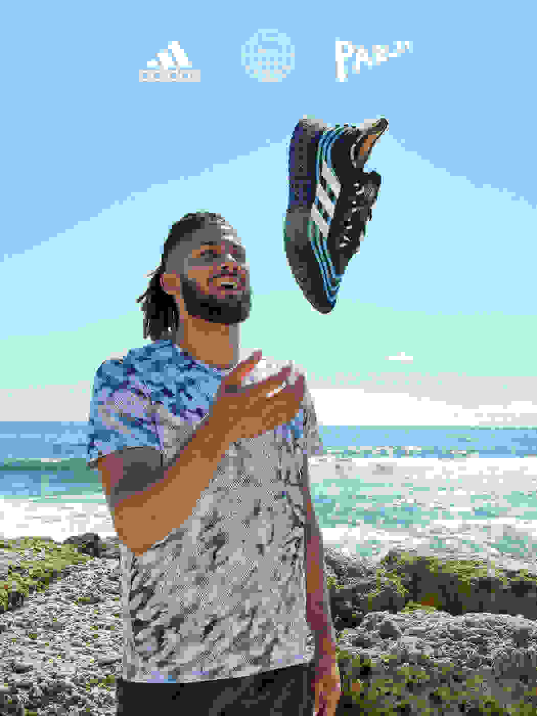 Fernando Tatís Jr. (Dominican, professional baseball player) holding a Parley shoe, with view of beach in the background.