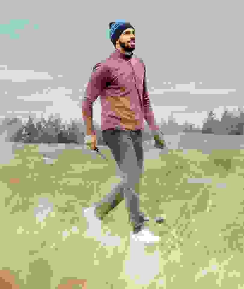 Man in adidas fleece golf apparel walks on a golf course.