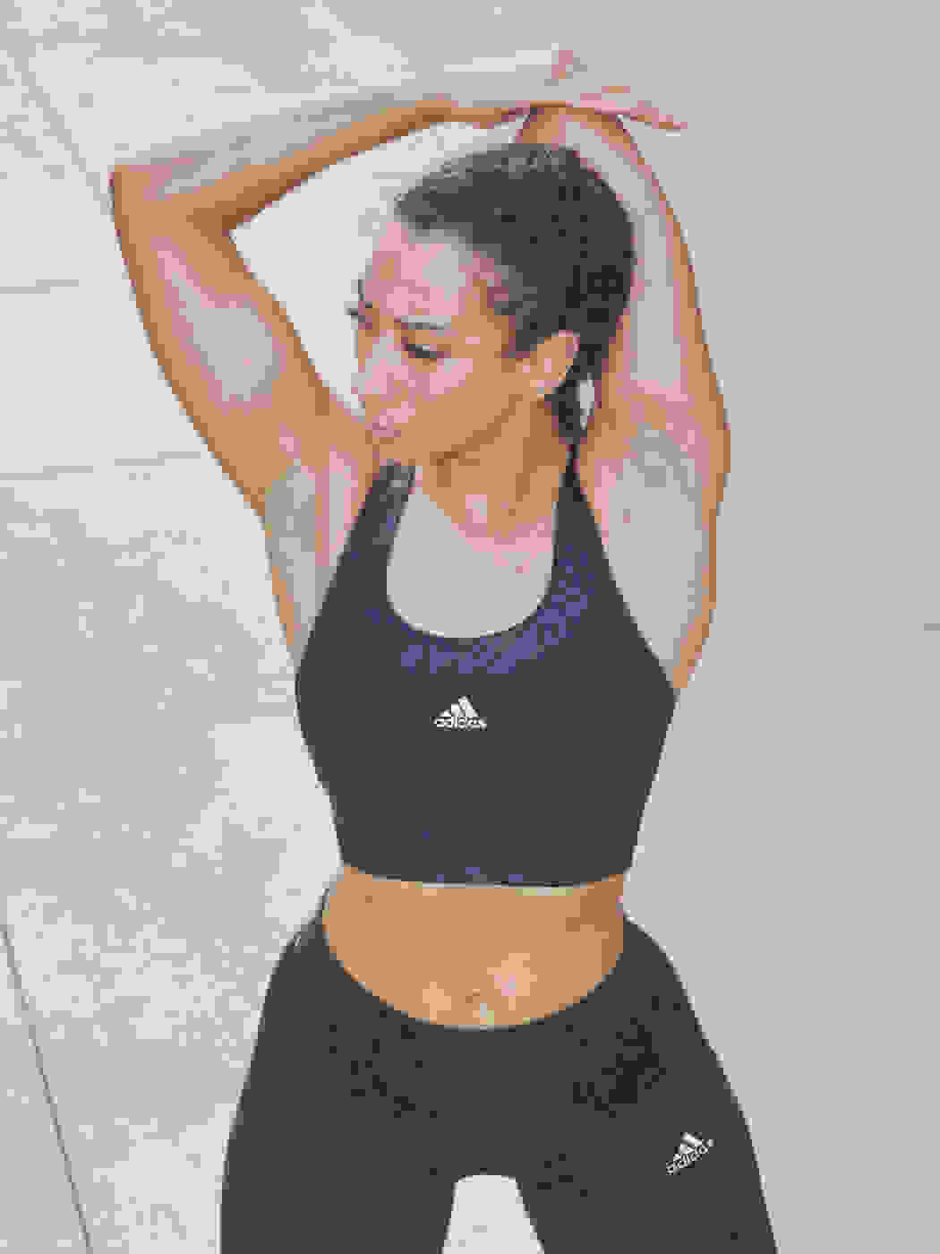 Image of an Athletic model stretching wearing navy blue tights and support bra co-ord