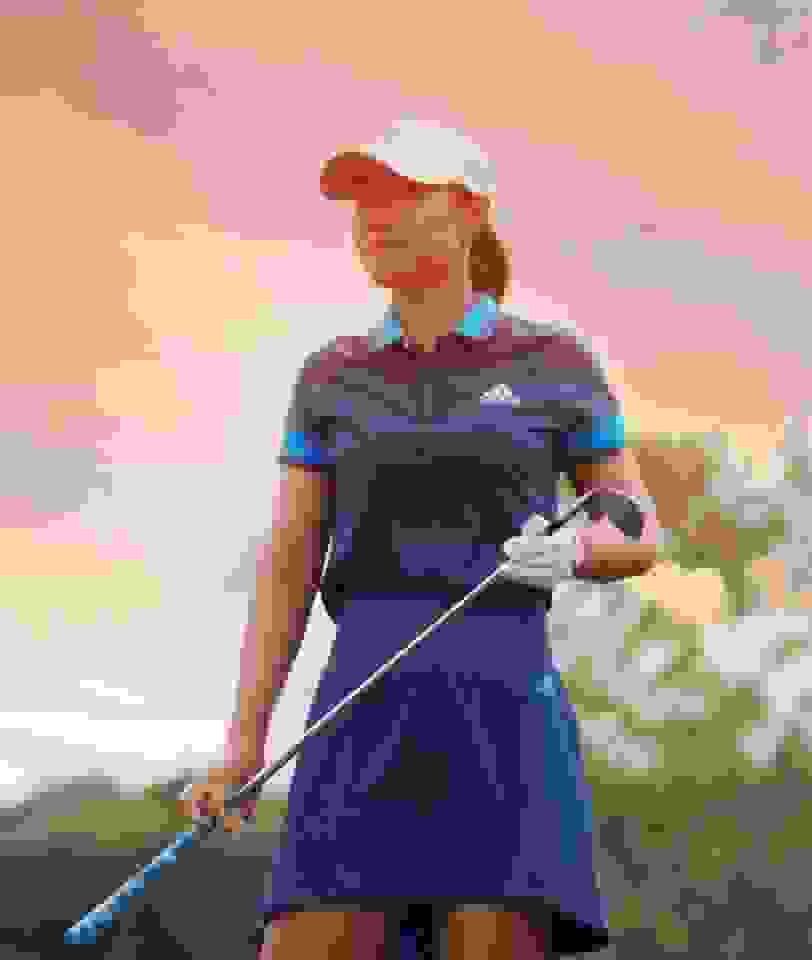 Danielle Kang holding a golf club in adidas skirt and shirt