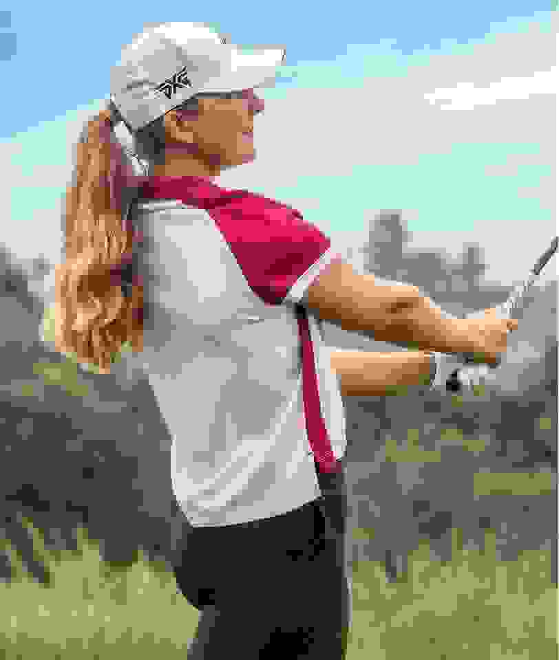 Linnea Strom swinging a golf club in adidas clothing.