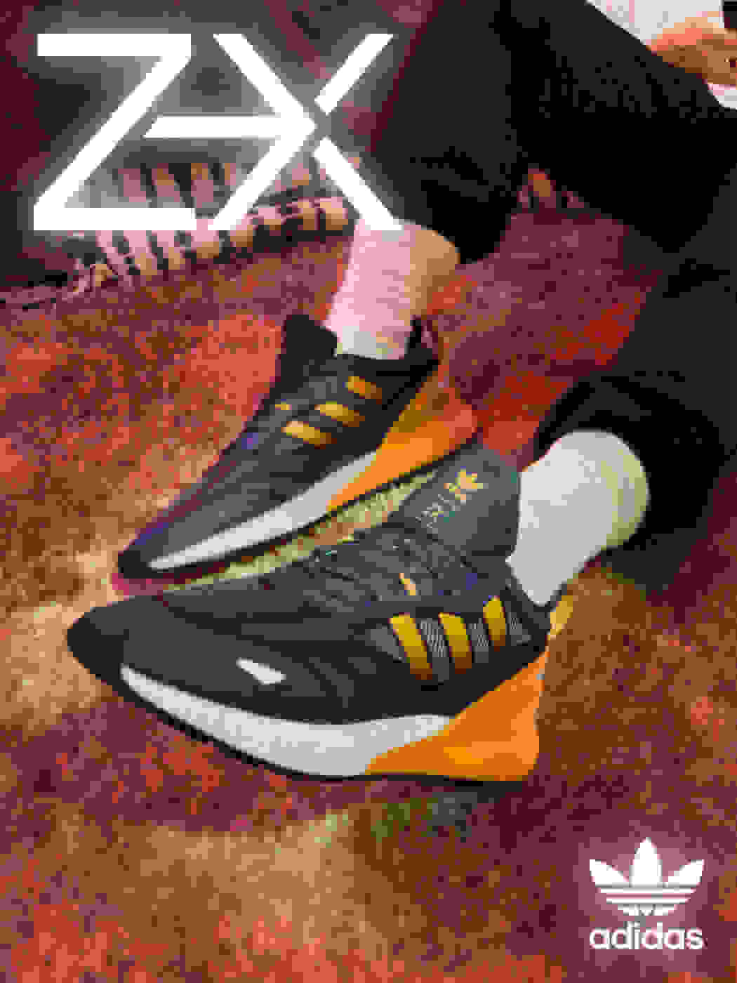 A model lounges on the carpet in front of a laptop wearing the ZX 2K Boost 2.0 with orange glow-inspired highlights on the heel and stripes.