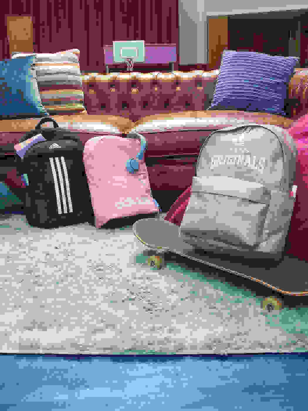 Three backpacks in front of couch inside school building