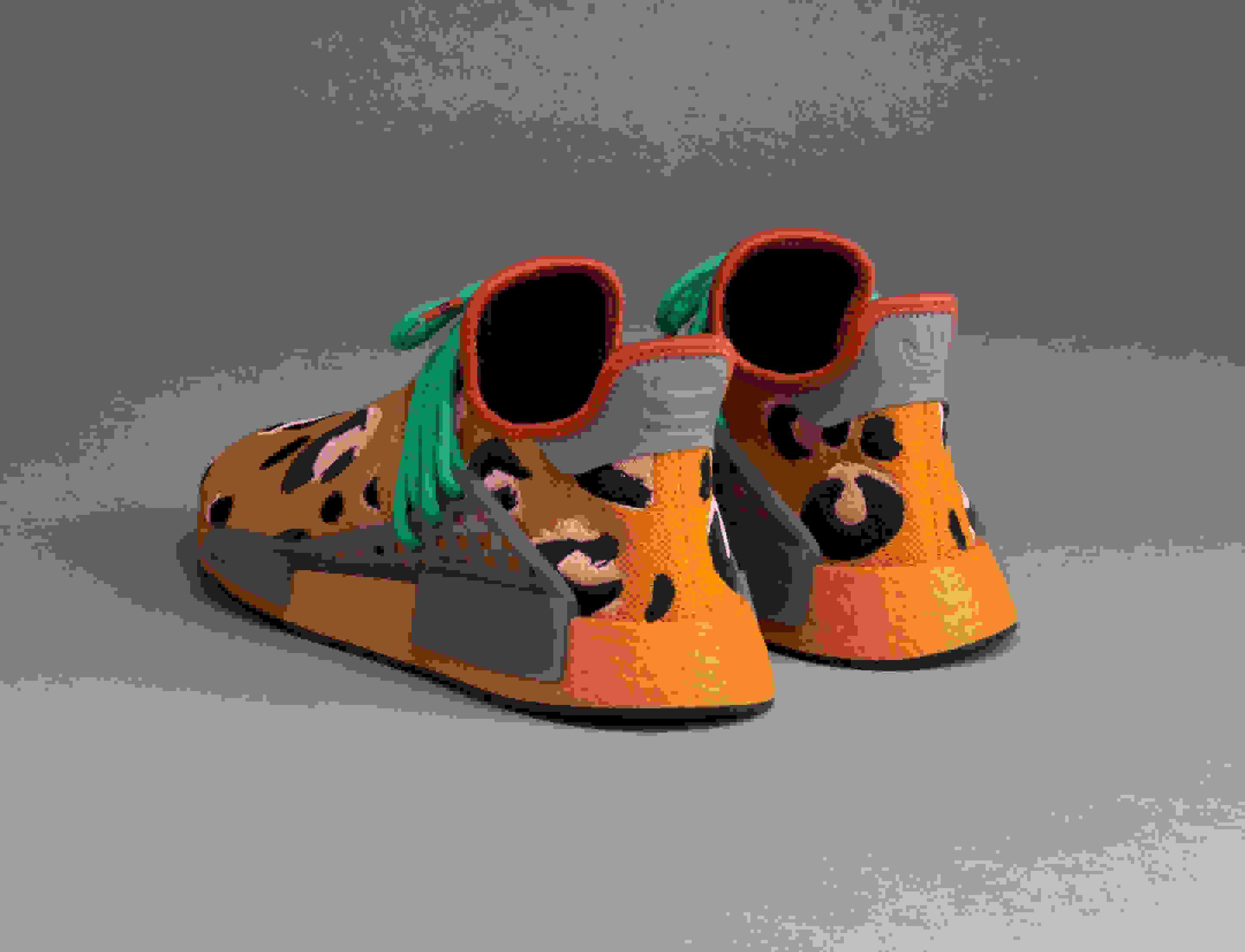 Pair of orange Hu NMD Animal Print shoes facing away