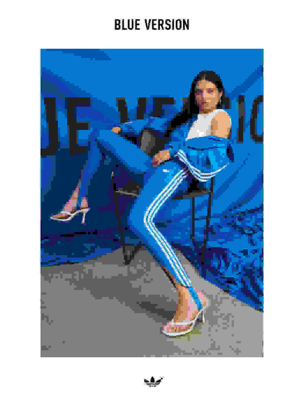 An image of Ganna Bogdan striking a pose on a chair wearing the Blue Version Beckenbauer tracksuit in bluebird and a pair of high heels.