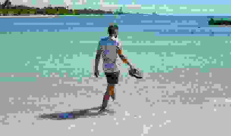 man walking into the ocean with 4DFWD X Parley shoes in his hand