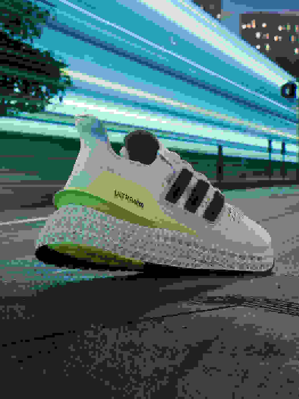 A yellow and white men's running shoe moves forward in an urban environment.