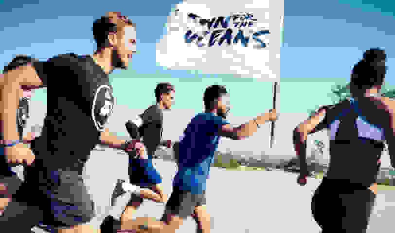 Runners running with the run for the oceans flag