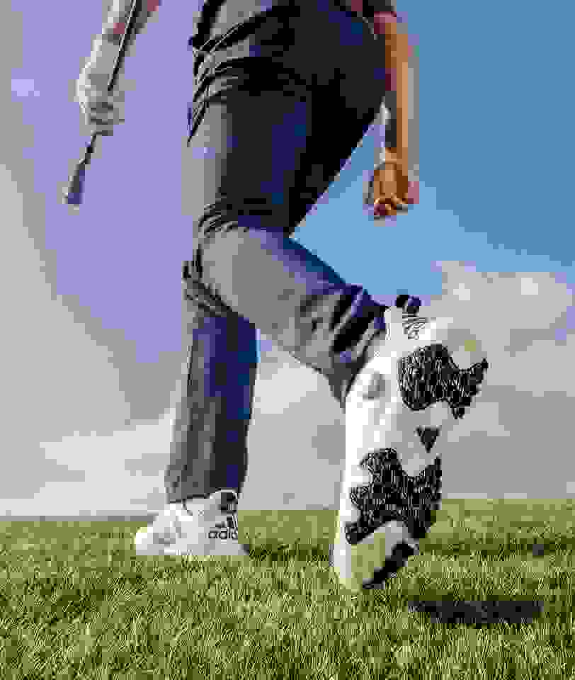 Golfer walks with golf club showing the bottom of the CODECHAOS golf shoe.
