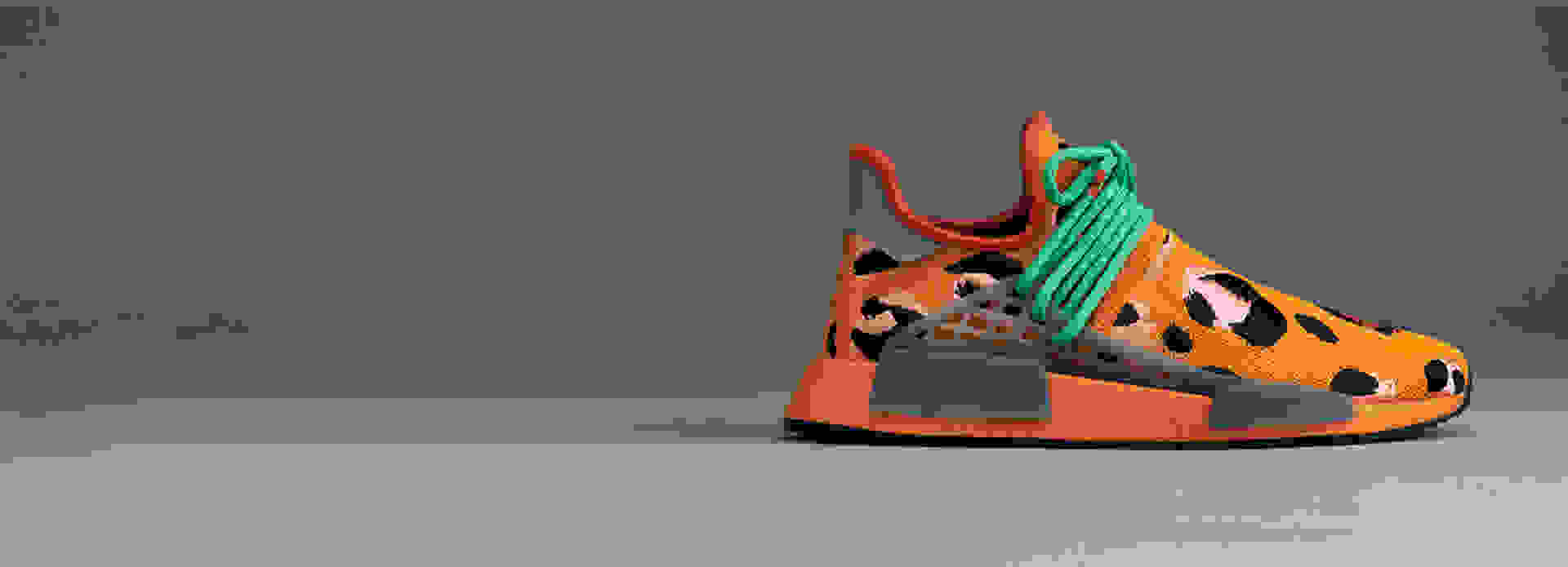 Side view of orange Hu NMD Animal Print shoes against gray background