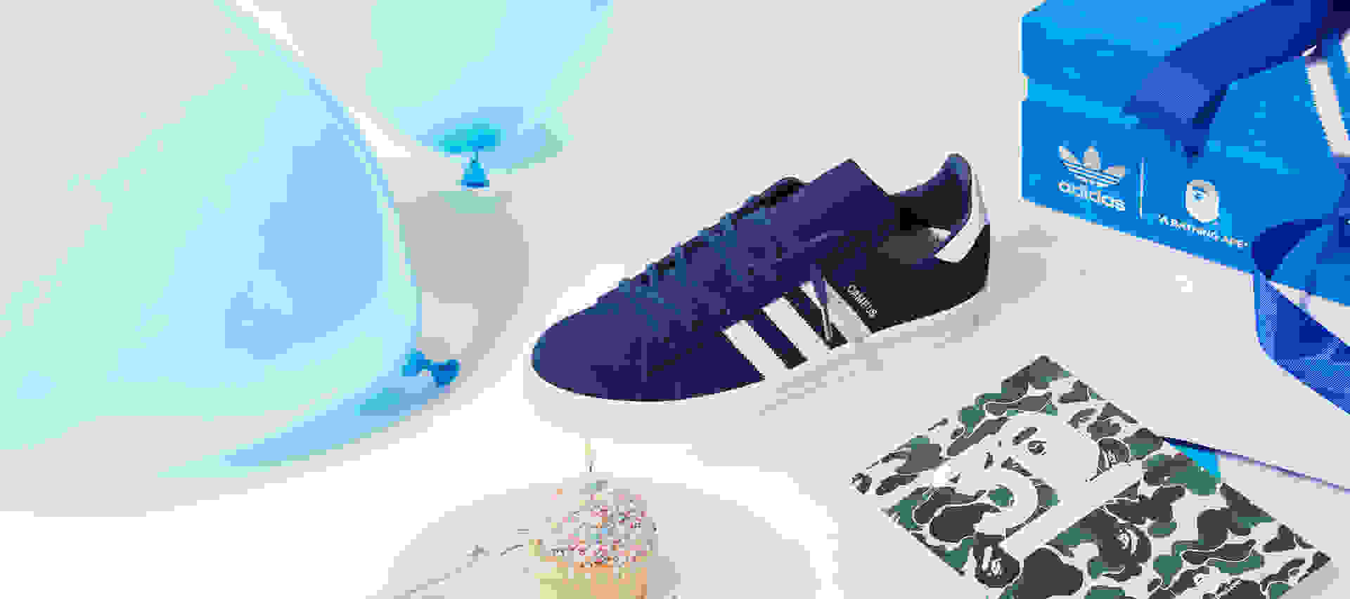 The adidas CAMPUS 80s BAPE® is pictured with a cupcake, balloons and an exclusive adidas x BAPE® shoebox.