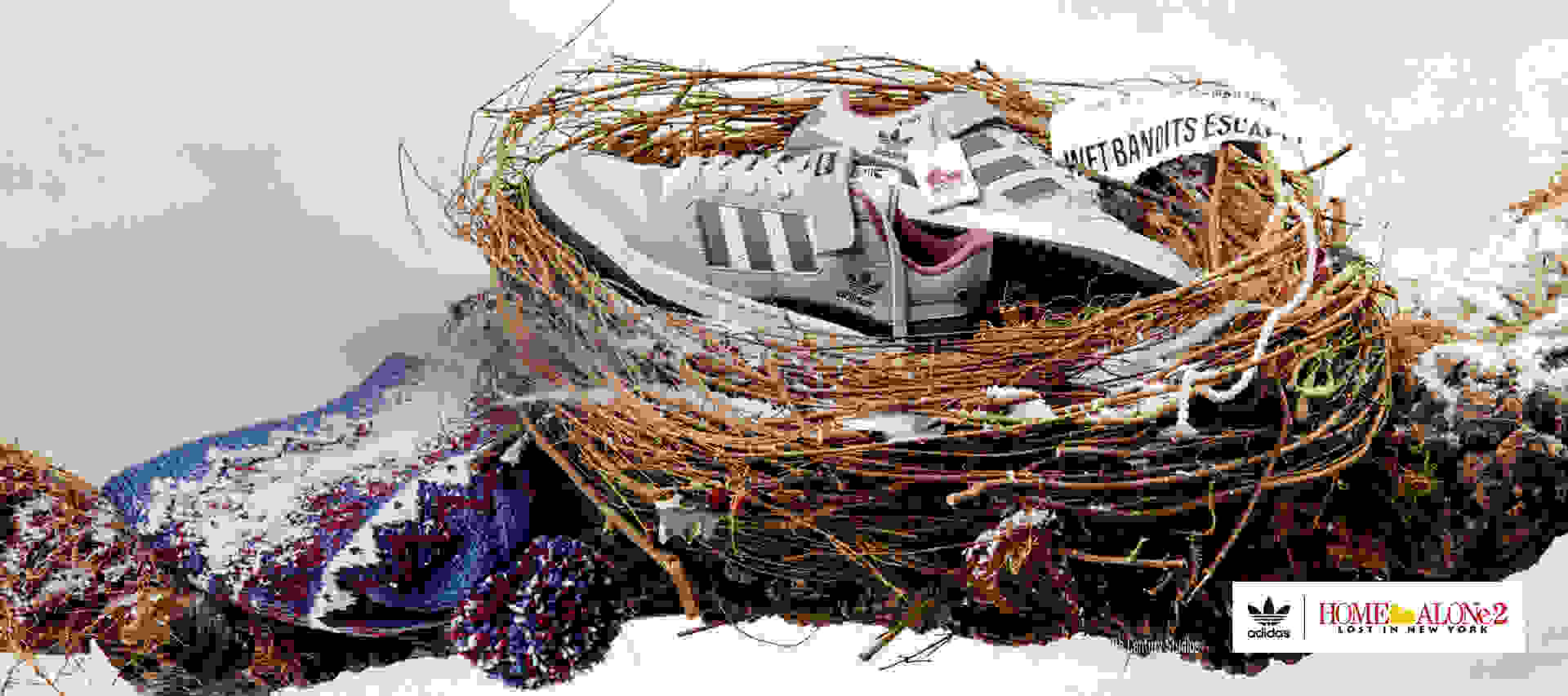 A pair of Forum Low Home Alone sneakers lie in a bird's nest on a snow-covered branch. Kevin's classic bobble hat lies next to it.
