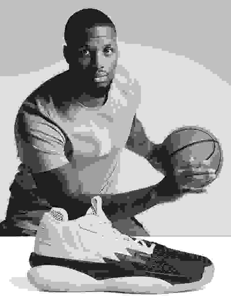 Professional basketball player Damian Lillard holding a basketball with a white and black shoe in the front.
