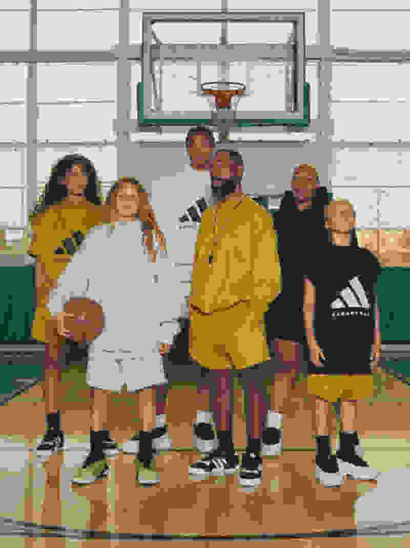 A coach stands on an indoor basketball court with five young players