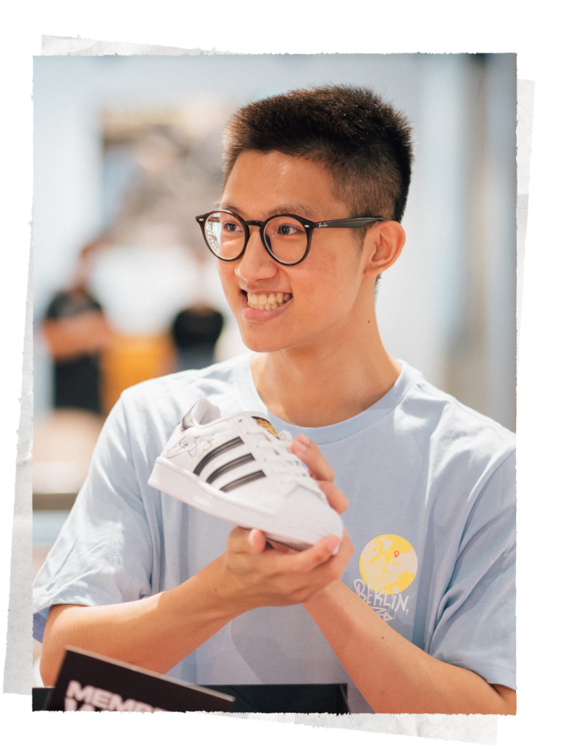 An image with a smiling man holding a sneaker in his hands