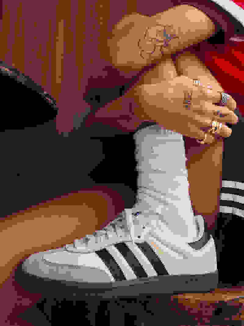 Female model wearing adidas Sambas with her foot in a chair.