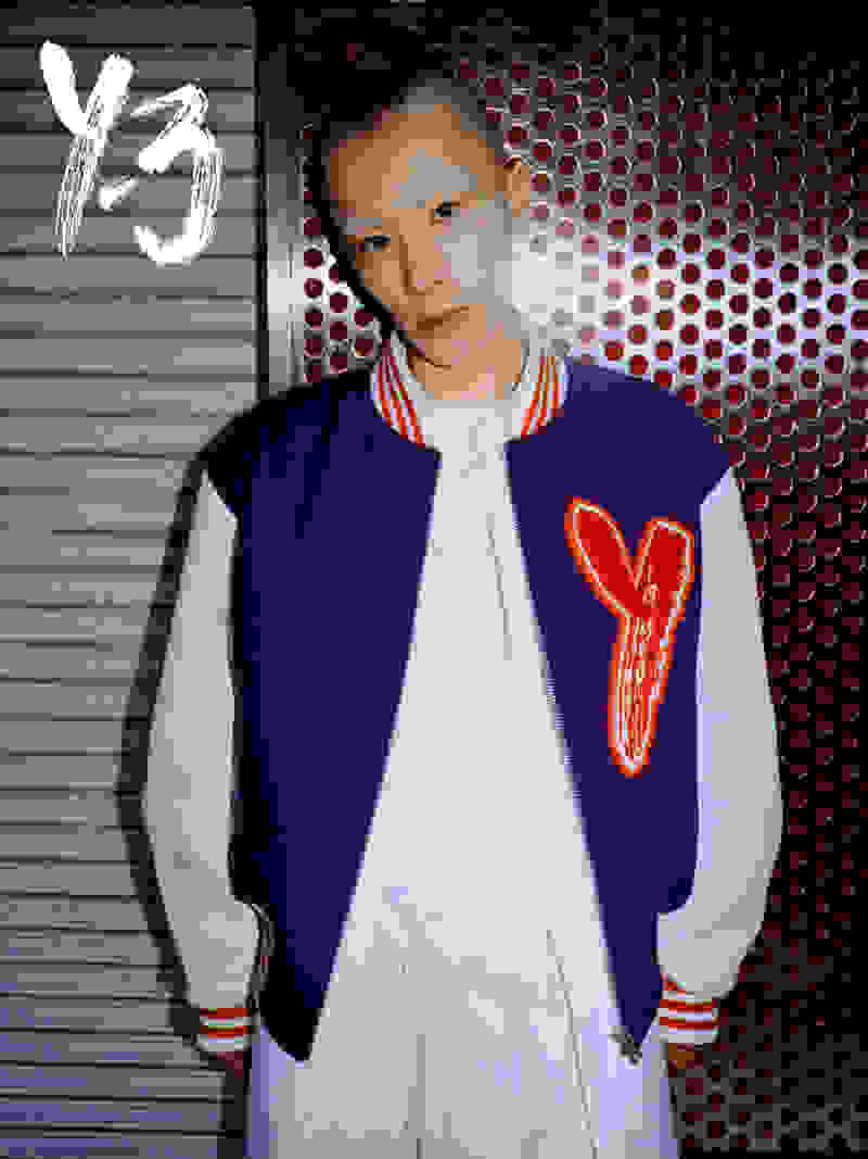 A man with a mohawk haircut and bleached eyebrows wears a purple and red Y-3 jacket while staring down the camera.