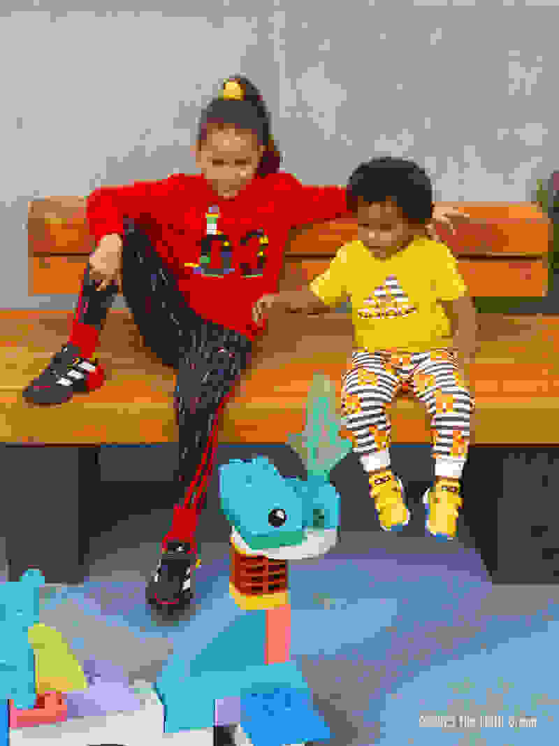 A little girl and infant boy sit on a bench watch a DUPLO® sea monster swim around.