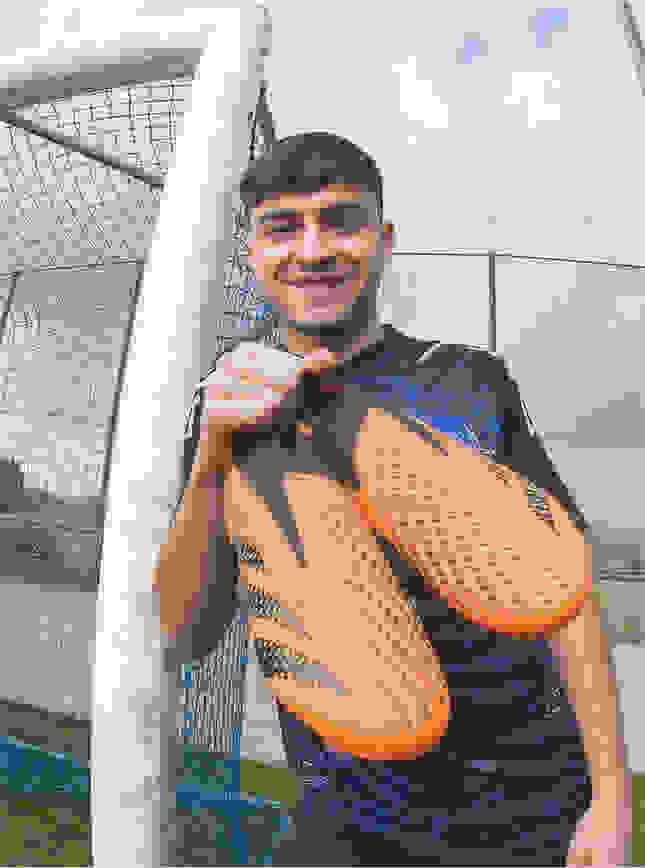 Visual of pedri holding his signed boots.