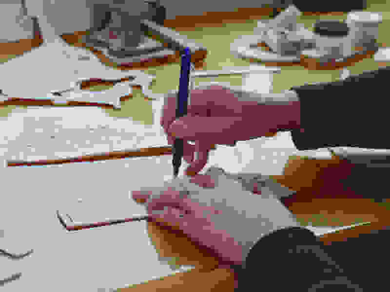 A man in a room drawing on paper with a pen