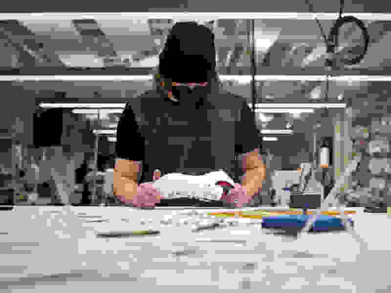 A man in a factory looking at the bottom of a shoe