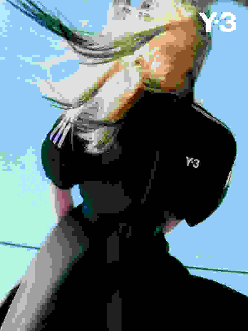 A woman with short black hair stares sternly into the camera while wearing black Y-3 apparel.