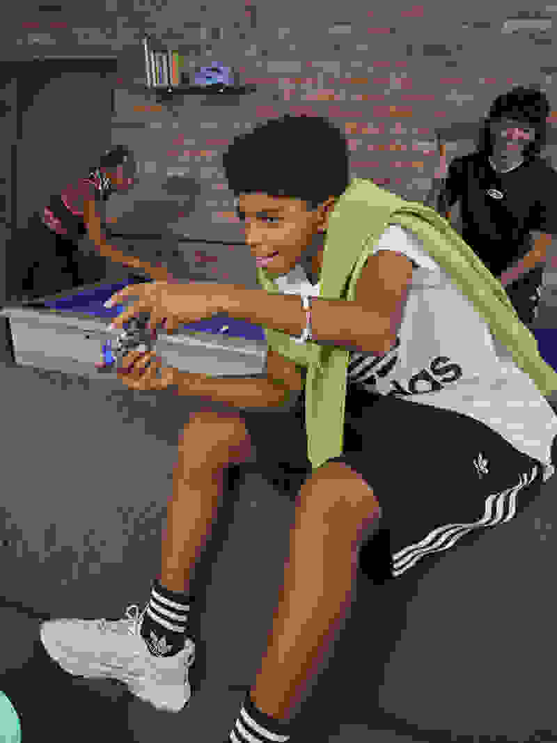 Image of smiling teens wearing adidas and hanging out together on the couch.