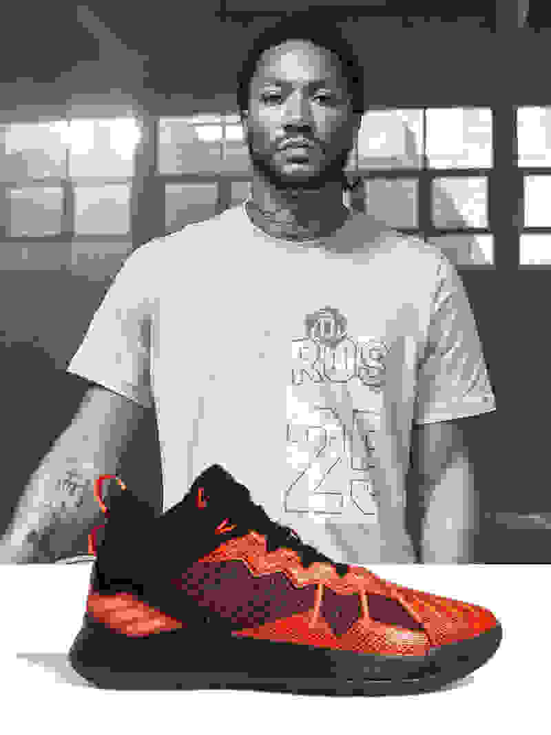 Professional basketball player Derrick Rose posing with a red and black shoe in the front.