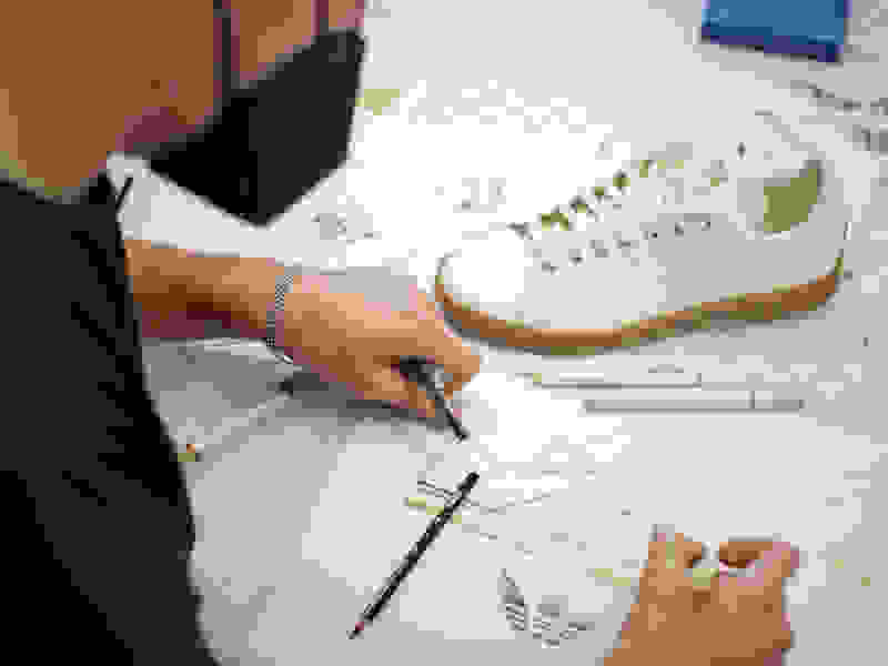 A designer drawing a shoe sketch of the Stan Smith Mylo