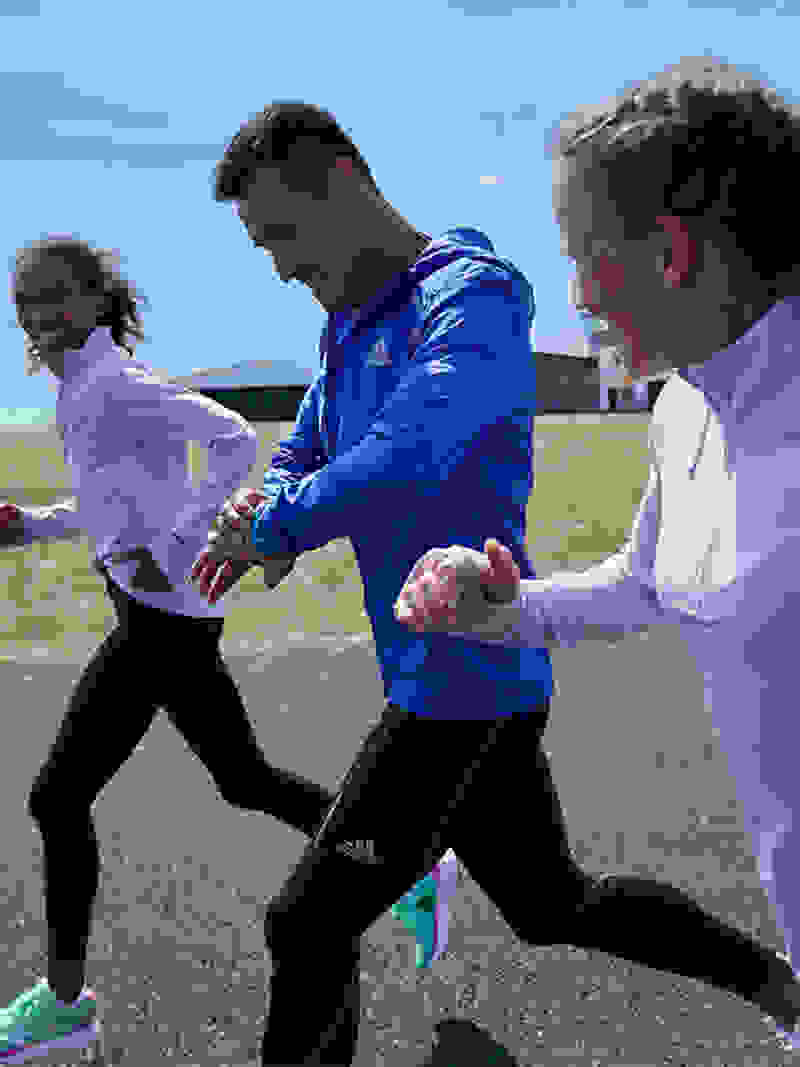 An edit that run-through various images showing the Adizero SL mens and women’s shoe. In the background a man ties his Adizero SL shoes preparing to go for a run. In the foreground image, 3 runners, two women and a man run along a dirt road wearing a the Adizero SL.
