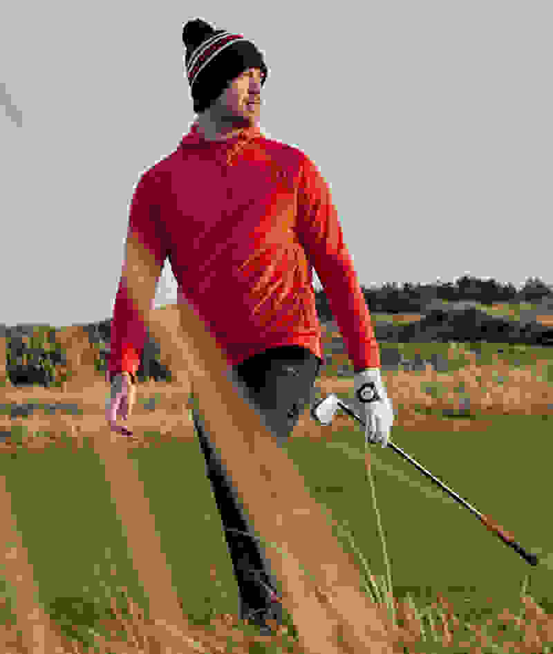 Man walks on golf course with a golf club.