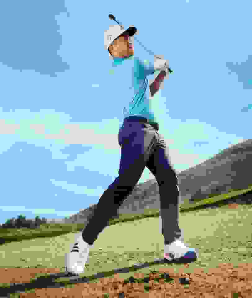 Xander Schauffele Swinging a golf club in adidas pants and shirt