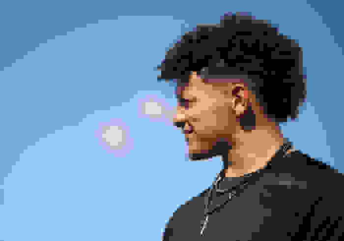 A candid side-portrait of Patrick Mahomes, smiling and looking out into the distance.