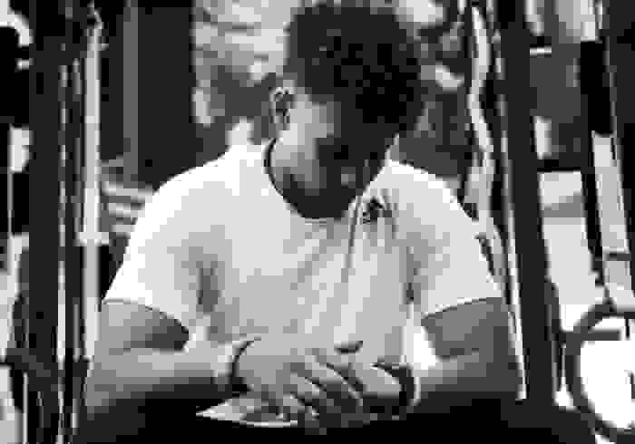 A black and white photograph of Patrick Mahomes, sitting in a gym, looking down, thoughtfully.