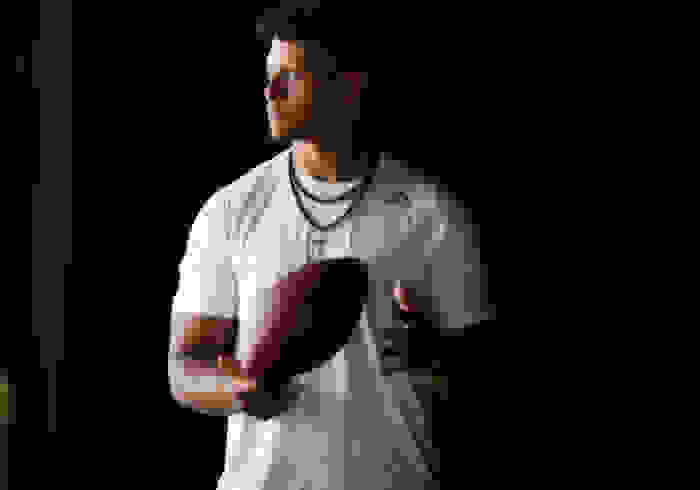 A candid portrait of Patrick Mahones, holding a football. He is looking out into the distance.