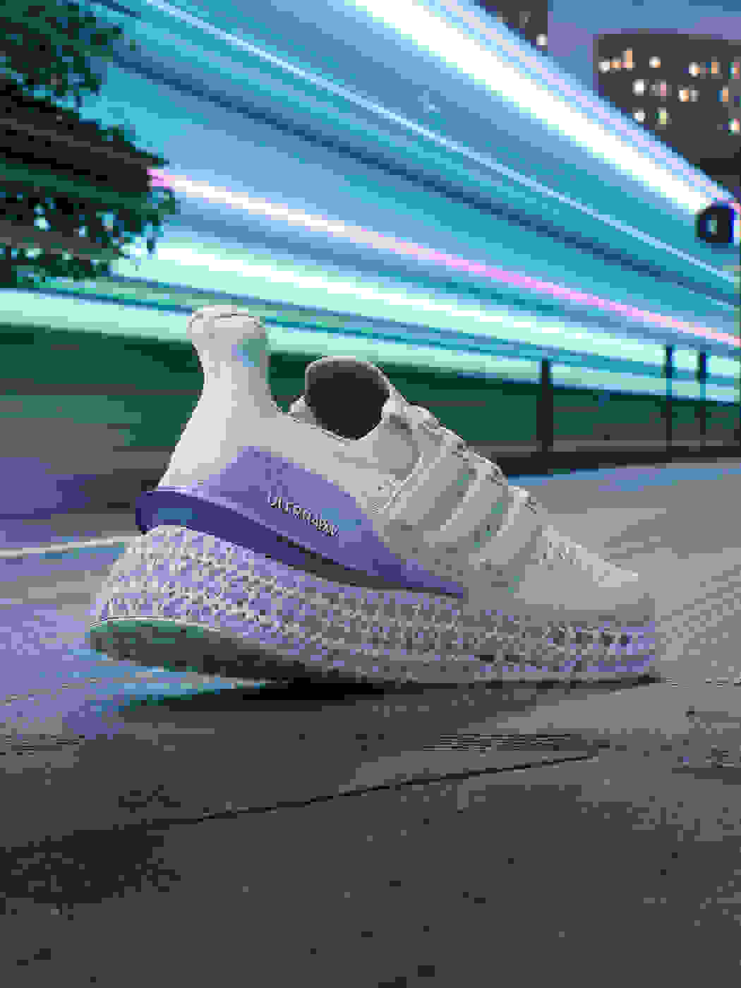 A purple and white women's running shoe moves forward in an urban environment.