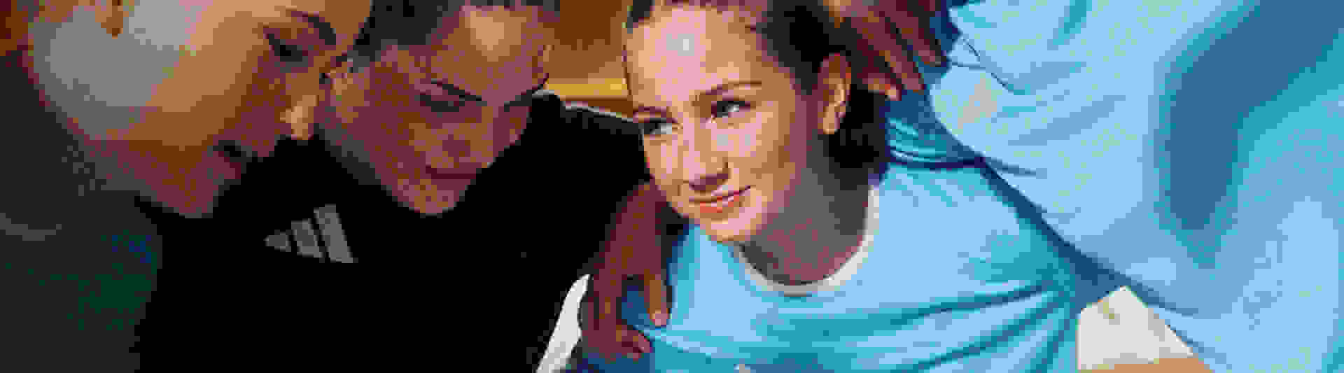 The image shows two individuals, a man and a woman, in close proximity, with the woman appearing to be smiling and the man looking at her affectionately.