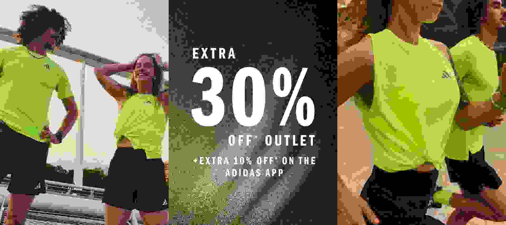 The image shows two people, a man and a woman, wearing bright neon green athletic tops, standing in front of a large sign advertising an extra 30% off outlet sale on the Adidas app.